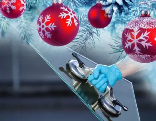 Hand with a light blue glove holding a glass outside. Red christmas ornaments